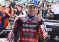 Marc Marquez tersenyum sambil mengepalkan tangan dengan pakaian balap Ducati Lenovo