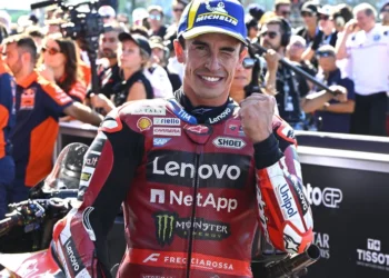 Marc Marquez tersenyum sambil mengepalkan tangan dengan pakaian balap Ducati Lenovo