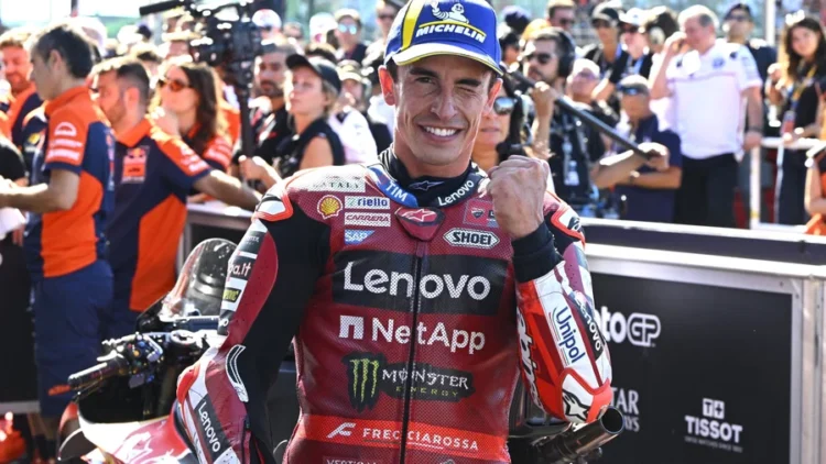 Marc Marquez tersenyum sambil mengepalkan tangan dengan pakaian balap Ducati Lenovo