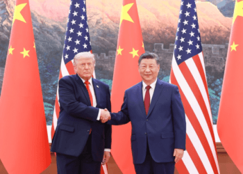 Donald Trump berjabat tangan dengan Xi Jinping di antara bendera Amerika Serikat dan China