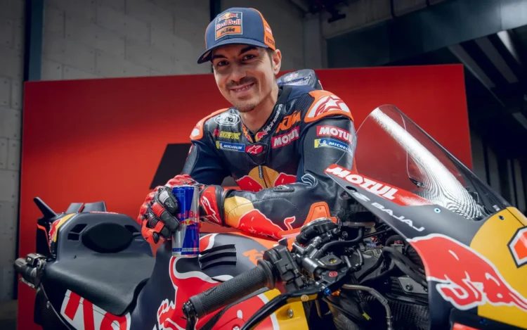 Maverick Vinales mengenakan baju balap dan topi KTM Red Bull di samping motor balap KTM