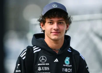 Pembalap Mercedes mengenakan topi Mercedes dan hoodie hitam berlogo Mercedes AMG dan Petronas