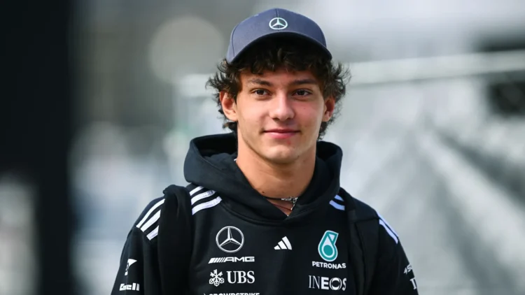 Pembalap Mercedes mengenakan topi Mercedes dan hoodie hitam berlogo Mercedes AMG dan Petronas