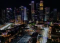 Pemandangan malam kawasan lintasan Formula 1 Marina Bay, Singapura, dengan gedung-gedung tinggi bercahaya, tribun penonton dan jalan sirkuit