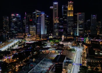 Pemandangan malam kawasan lintasan Formula 1 Marina Bay, Singapura, dengan gedung-gedung tinggi bercahaya, tribun penonton dan jalan sirkuit