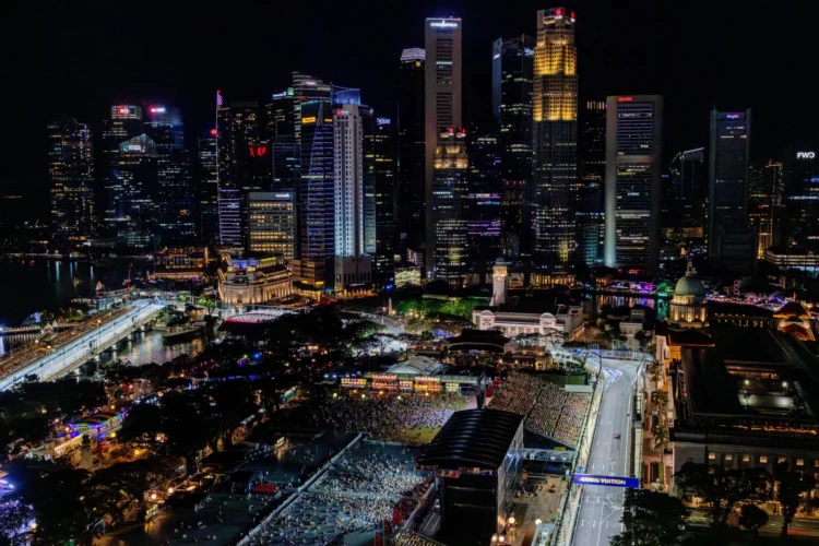 Pemandangan malam kawasan lintasan Formula 1 Marina Bay, Singapura, dengan gedung-gedung tinggi bercahaya, tribun penonton dan jalan sirkuit