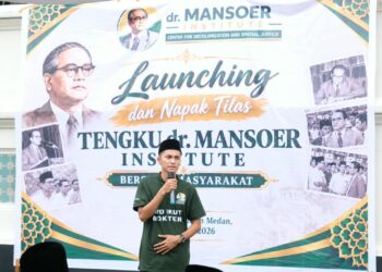 Seorang pria berbicara menggunakan mikrofon di depan spanduk peluncuran Tengku dr. Mansoer Institute