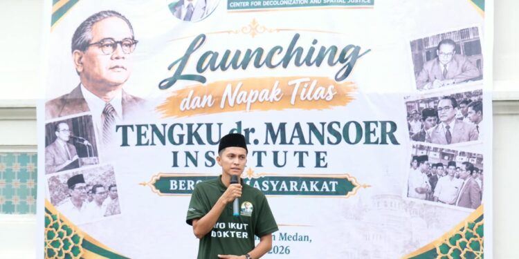 Seorang pria berbicara menggunakan mikrofon di depan spanduk peluncuran Tengku dr. Mansoer Institute