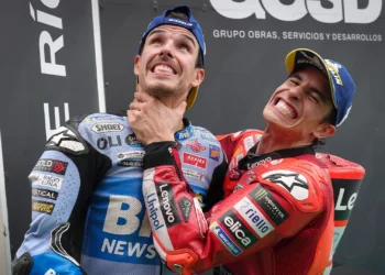 Dua pembalap MotoGP mengenakan baju balap biru Gresini dan merah Ducati serta topi Michelin, tampak bercanda bersama