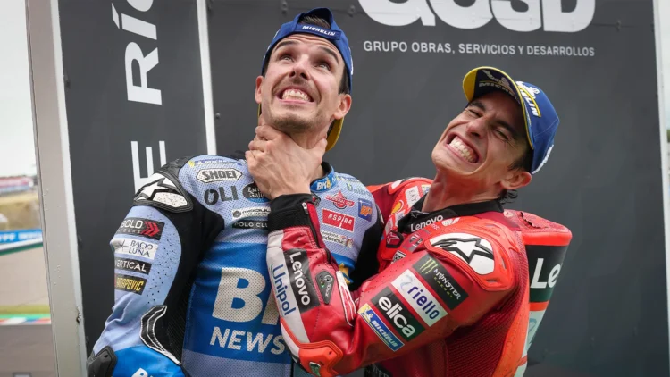 Dua pembalap MotoGP mengenakan baju balap biru Gresini dan merah Ducati serta topi Michelin, tampak bercanda bersama