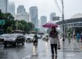 Seorang warga membawa payung saat melintas di Kawasan Senayan, Jakarta (Ilustrasi AI Bulatantimes