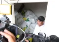 Seorang pria berdiri di dekat tumpukan karung beras ketika wartawan merekam di lokasi pemeriksaan