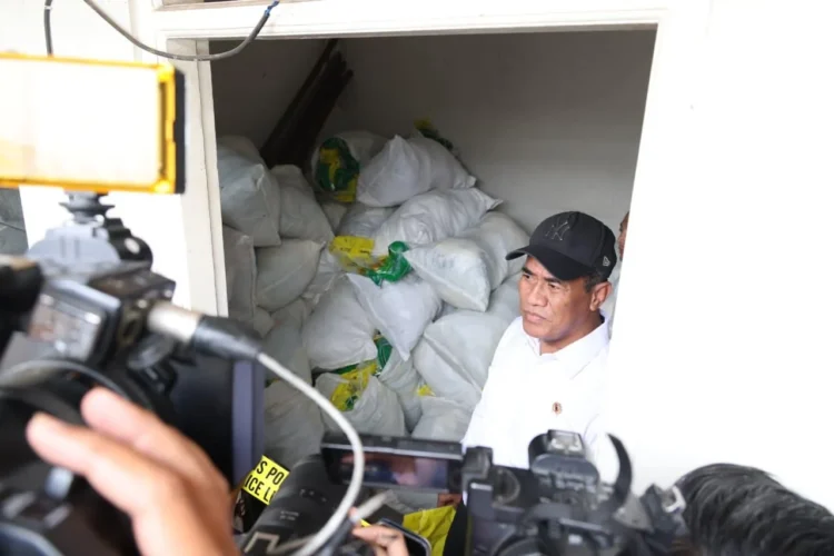 Seorang pria berdiri di dekat tumpukan karung beras ketika wartawan merekam di lokasi pemeriksaan