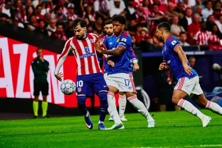 Pemain Atletico Madrid berseragam merah-putih menguasai bola saat dihadang dua pemain Manchester United berbaju biru