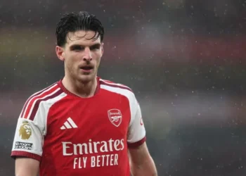 Declan Rice mengenakan seragam merah putih Arsenal di lapangan saat hujan