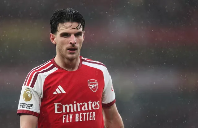 Declan Rice mengenakan seragam merah putih Arsenal di lapangan saat hujan