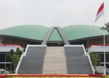 Tampak depan Gedung DPR RI dengan tangga utama, atap hijau, dan bendera Merah Putih