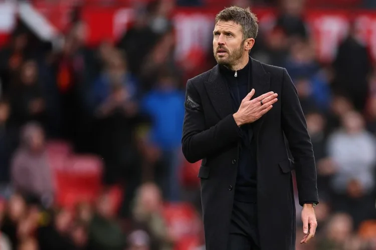Michael Carrick mengenakan mantel hitam di sisi lapangan sepak bola