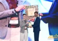 Dua orang berdiri di panggung sambil memegang plakat GamingonPhone Awards 2026, dengan layar acara penghargaan di belakangnya