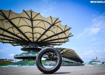Ban balap Michelin berdiri di permukaan Sirkuit Sepang dengan tribun utama di latar belakang