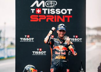 Pedro Acosta mengenakan pakaian balap Red Bull KTM dan merayakan kemenangan di depan papan Tissot Sprint