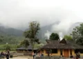 Bangunan pemandian dan pengunjung di kawasan pegunungan yang berkabut dengan pepohonan di sekitarnya