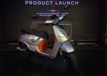 Peugeot Django Evo 125 berwarna perak dengan aksen jingga dipajang di panggung peluncuran produk.