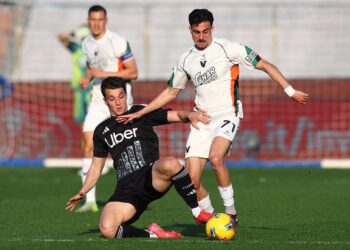 Pemain Como berseragam hitam berusaha merebut bola dari pemain Venezia berseragam putih dalam pertandingan sepak bola