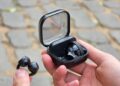 Earbuds jepit Samsung Galaxy Buds On berwarna hitam, satu di tangan dan satu dalam casing pengisian daya terbuka