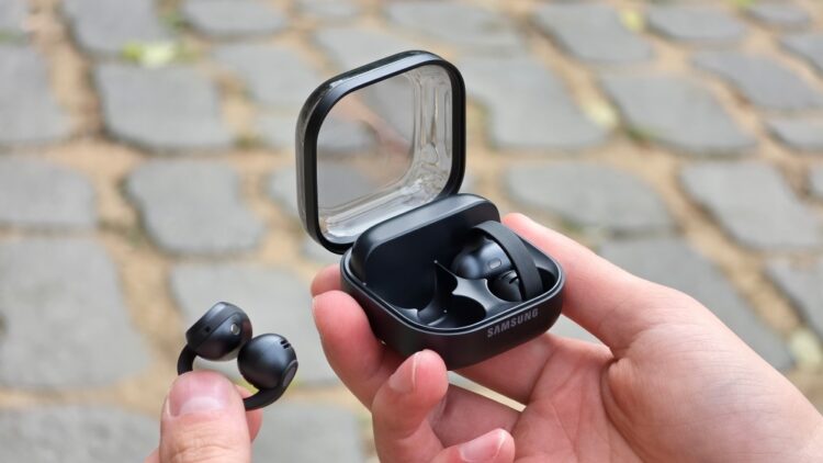 Earbuds jepit Samsung Galaxy Buds On berwarna hitam, satu di tangan dan satu dalam casing pengisian daya terbuka