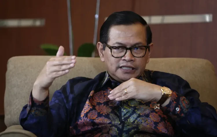 Pramono Anung mengenakan kacamata dan kemeja batik sambil berbicara dengan tangan terangkat saat duduk di kursi
