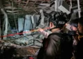 Petugas polisi memakai helm memeriksa puing dan rangka bangunan yang rusak di lokasi ledakan Pasar Cimanggis