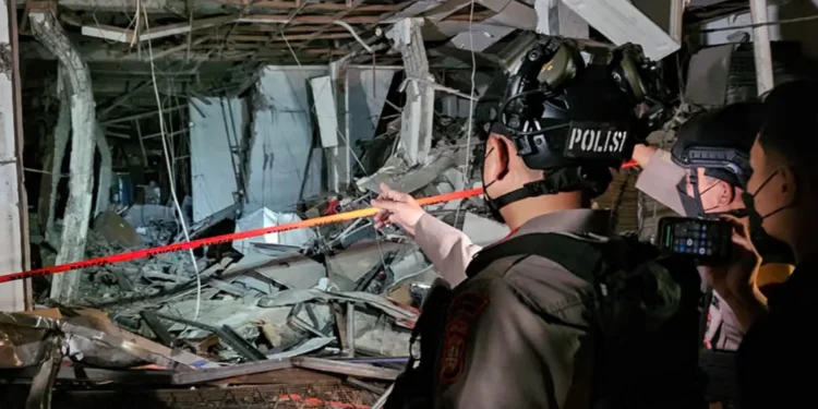 Petugas polisi memakai helm memeriksa puing dan rangka bangunan yang rusak di lokasi ledakan Pasar Cimanggis