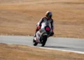 Pembalap Moto3 mengendarai motor bernomor 9 di lintasan balap dengan rumput kering di sekeliling sirkuit