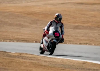 Pembalap Moto3 mengendarai motor bernomor 9 di lintasan balap dengan rumput kering di sekeliling sirkuit