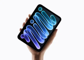 Tablet iPad mini berwarna hitam dalam genggaman tangan dengan tampilan grafis biru dan ungu pada layar