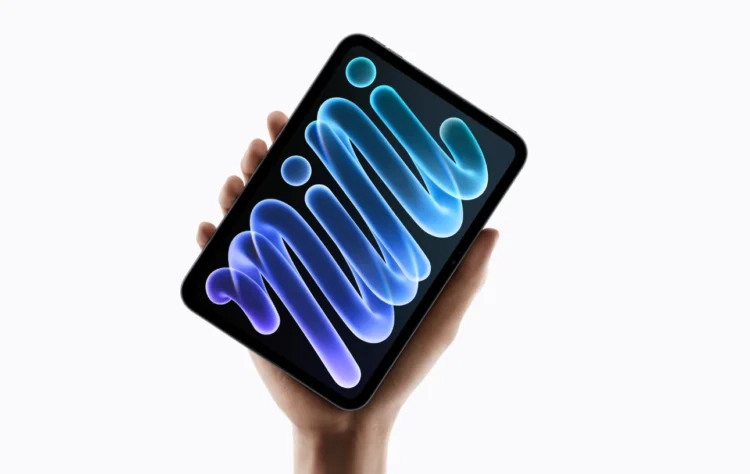Tablet iPad mini berwarna hitam dalam genggaman tangan dengan tampilan grafis biru dan ungu pada layar