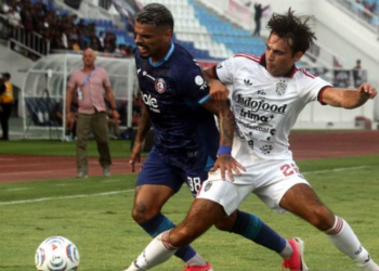 Pemain Arema FC berseragam biru gelap dan Bali United berseragam putih berduel memperebutkan bola
