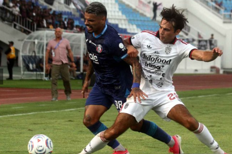 Pemain Arema FC berseragam biru gelap dan Bali United berseragam putih berduel memperebutkan bola