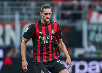 Adrien Rabiot mengenakan seragam merah hitam AC Milan di lapangan