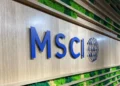 Logo bertuliskan MSCI berwarna biru pada dinding dengan panel tanaman hijau