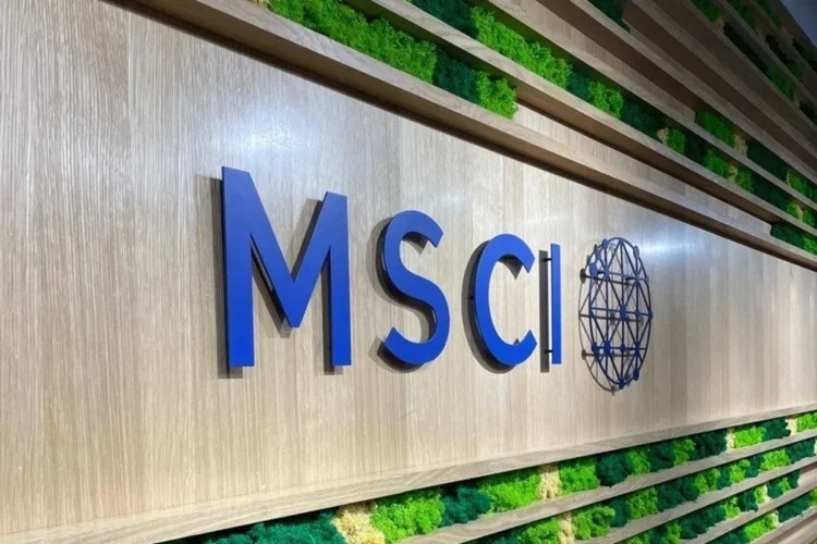 Logo bertuliskan MSCI berwarna biru pada dinding dengan panel tanaman hijau