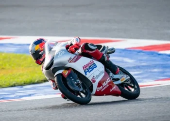 Pembalap Honda Team Asia mengendarai motor balap putih dan merah saat menikung di lintasan