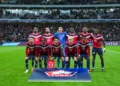 Sebelas pemain Lille mengenakan seragam merah dan biru berpose bersama di lapangan sebelum pertandingan Liga Champions.