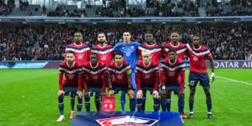 Sebelas pemain Lille mengenakan seragam merah dan biru berpose bersama di lapangan sebelum pertandingan Liga Champions.