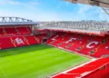 Bagian dalam Stadion Anfield milik Liverpool FC dengan tribune merah dan lapangan hijau