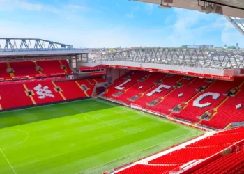 Bagian dalam Stadion Anfield milik Liverpool FC dengan tribune merah dan lapangan hijau