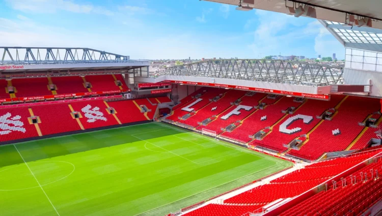 Bagian dalam Stadion Anfield milik Liverpool FC dengan tribune merah dan lapangan hijau