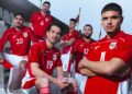 Lima pemain Timnas Indonesia mengenakan seragam merah berpose di tribun stadion.