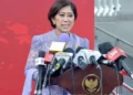 Menteri Komunikasi dan Digital Meutya Hafid berbicara di podium dengan beberapa mikrofon media di depannya